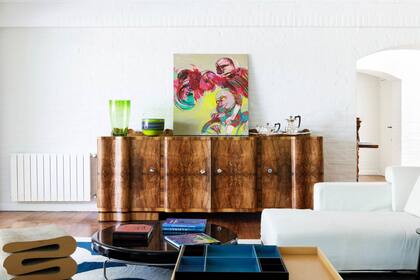 Un fabuloso mueble francés de raíz de nogal comprado en un mercado de antigüedades sostiene una obra de Raquel Forner.